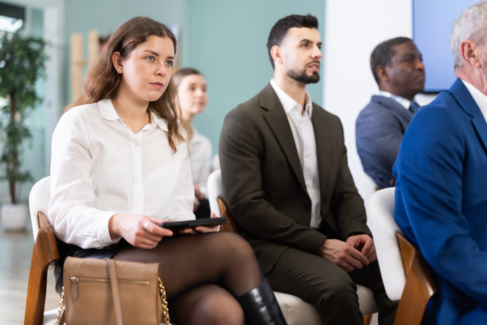 Young woman listens to presentation in conference room