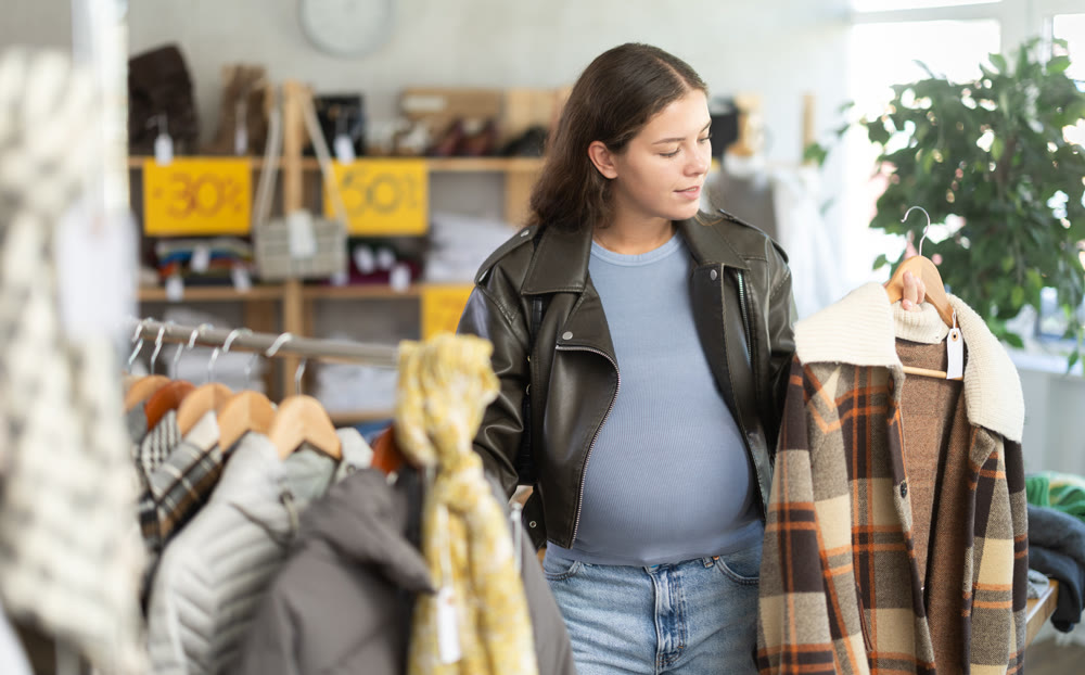 Pregnant woman chooses plaid jacket in clothing store
