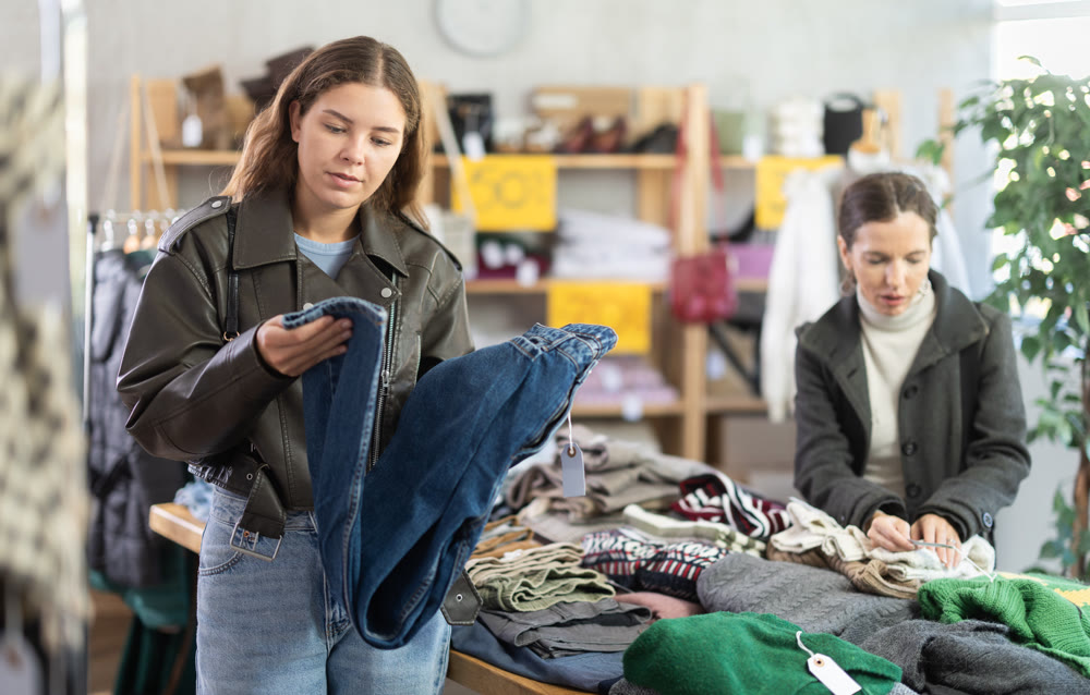 Young woman choosing jeans in clothing store