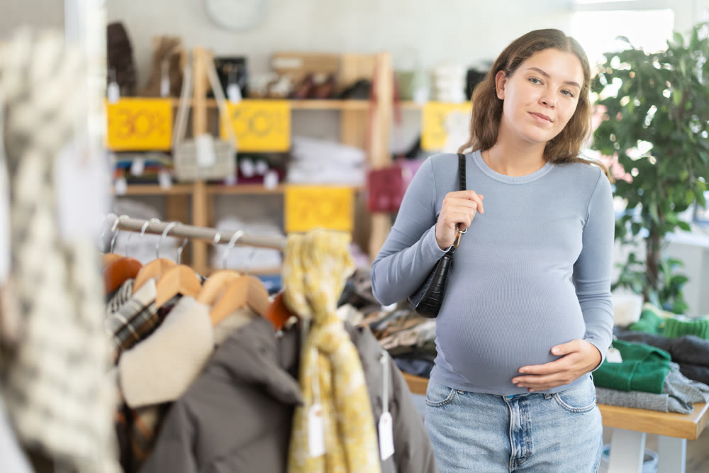 Pregnant woman choosing outerwear in clothing store