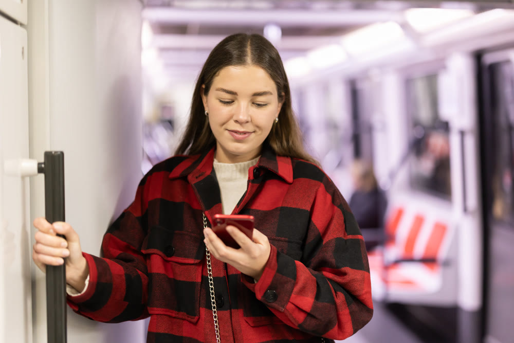 Girl is standing with phone in subway car, getting to work