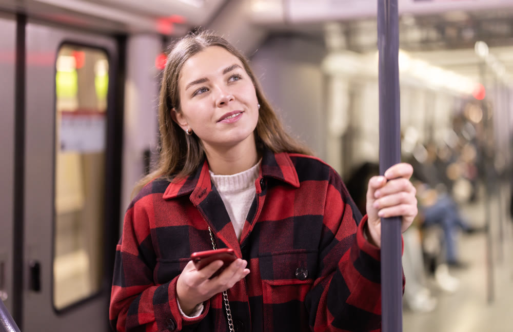 Girl is standing with phone in subway car, getting to work