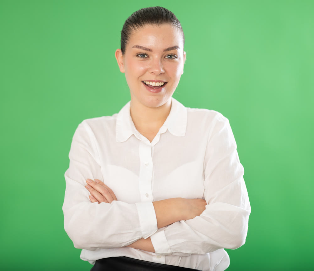 Portrait of happy girl in a white blouse and black skirt on green background