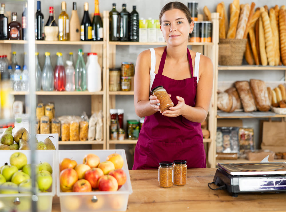 Young female seller offering lentils in grocery store