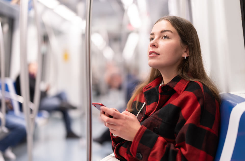 Girl sit in tram car with smartphone, getting to work