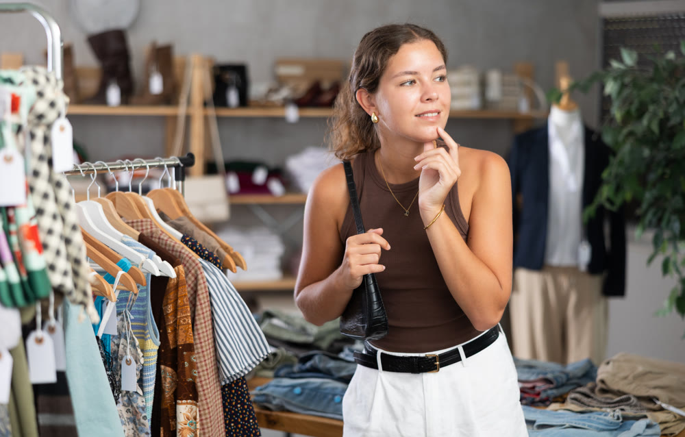 Young woman comes to boutique and looks at clothes