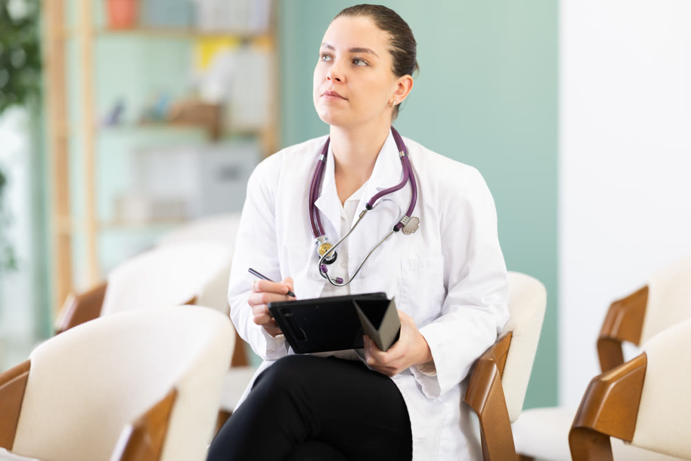 Attentive young girl medical student sitting and listening lecture, taking notes on tablet in auditory or lecture hall