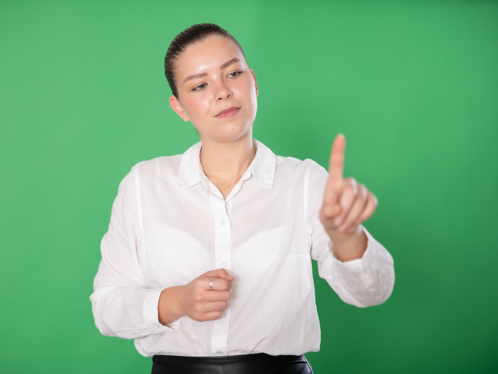 Girl in business clothes on green screen background moves her finger in air