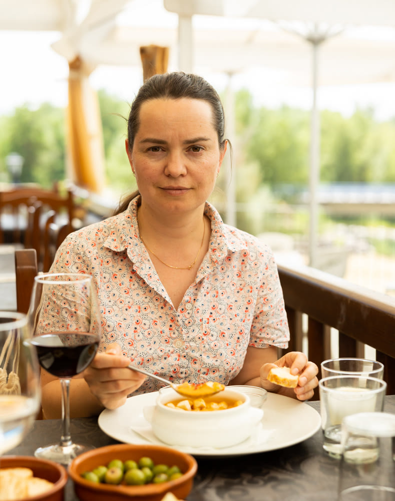 Positive woman eating tomato soup Gazpacho with bread