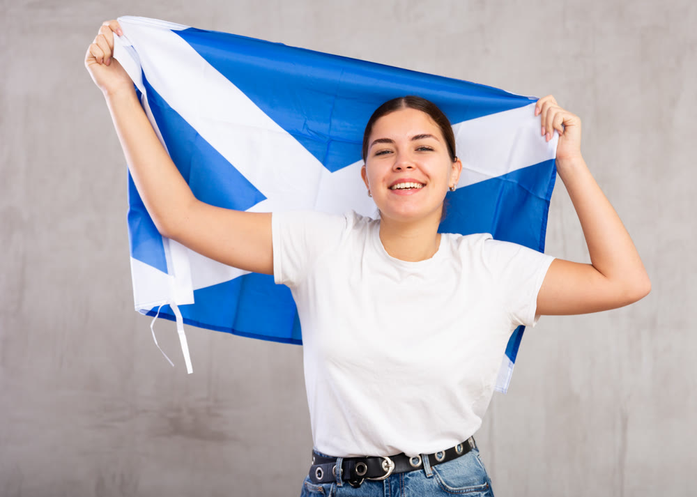 Positive young girl with Scotland flag rooting for your favorite team