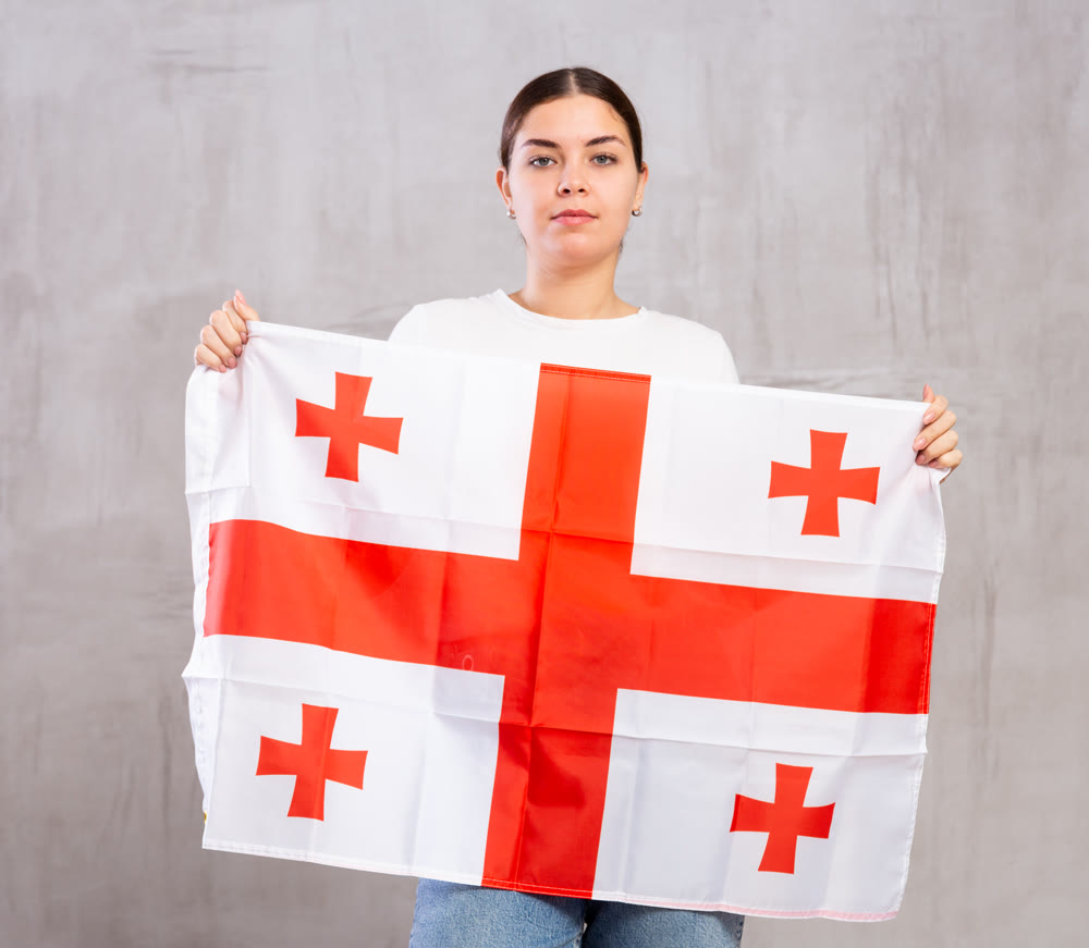 Calm girl stands with flag of Georgia.Isolated on gray background