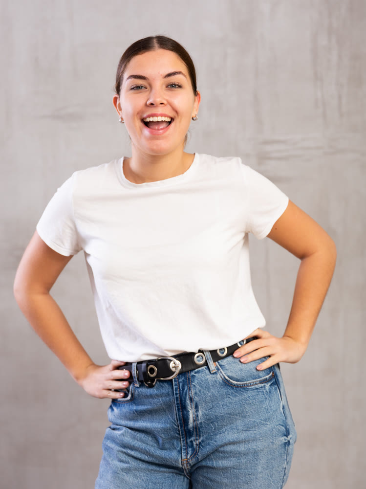 Cheery young woman posing happily against gray background