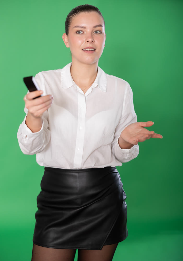 Girl in strict and business-like outfit with remote control in her hands.