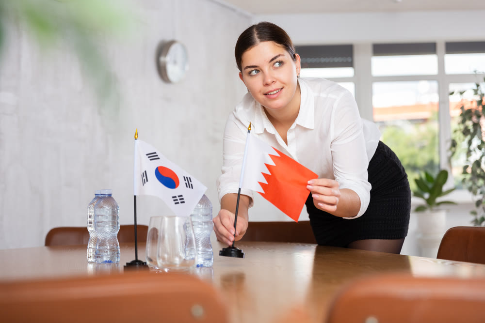 Businesswoman arranging the flags of South Korea and Bahrain for presentation and negotiations