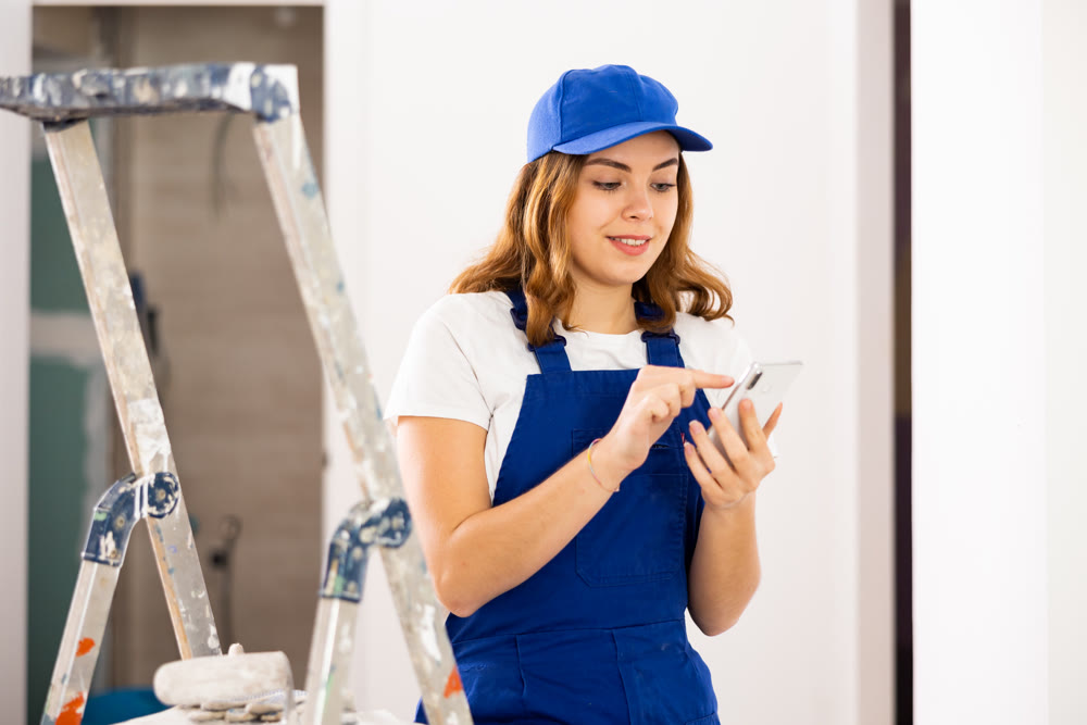 Female construction worker using smartphone in apartment