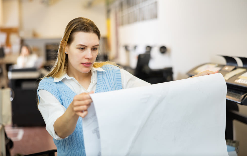 Printing office wokrer looking at large format paper