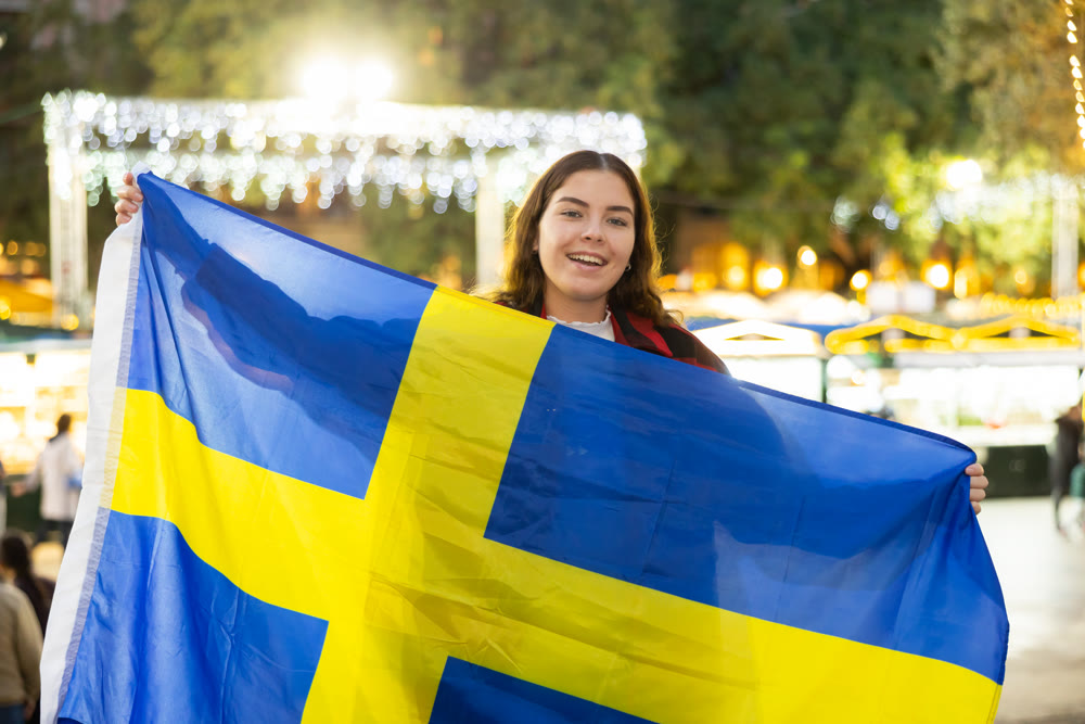 Young woman waving Swedish flag at the New Year street fair