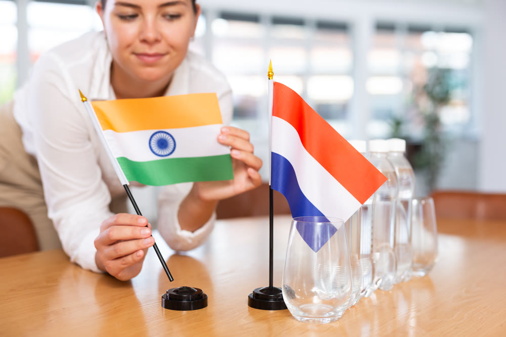 Blurry girl set midget flags of Netherlands and India before international negotiations