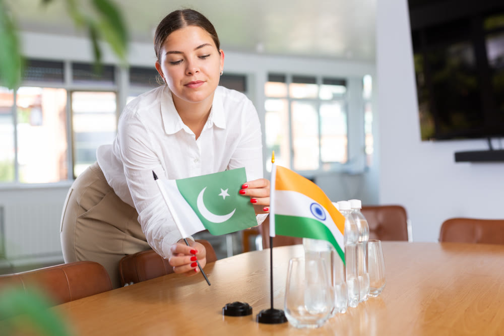 Young lady sets miniatures flags of India and Pakistan for international negotiations
