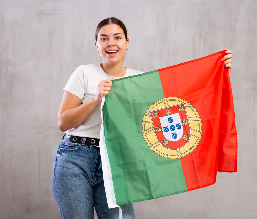 Happy girl stands with flag of Portugal. Isolated on gray background