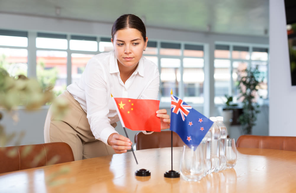 Preparing for business negotiations - woman sets small flags of countries of China and Australia on table