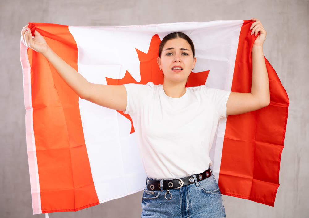Sad young woman holding Canada flag