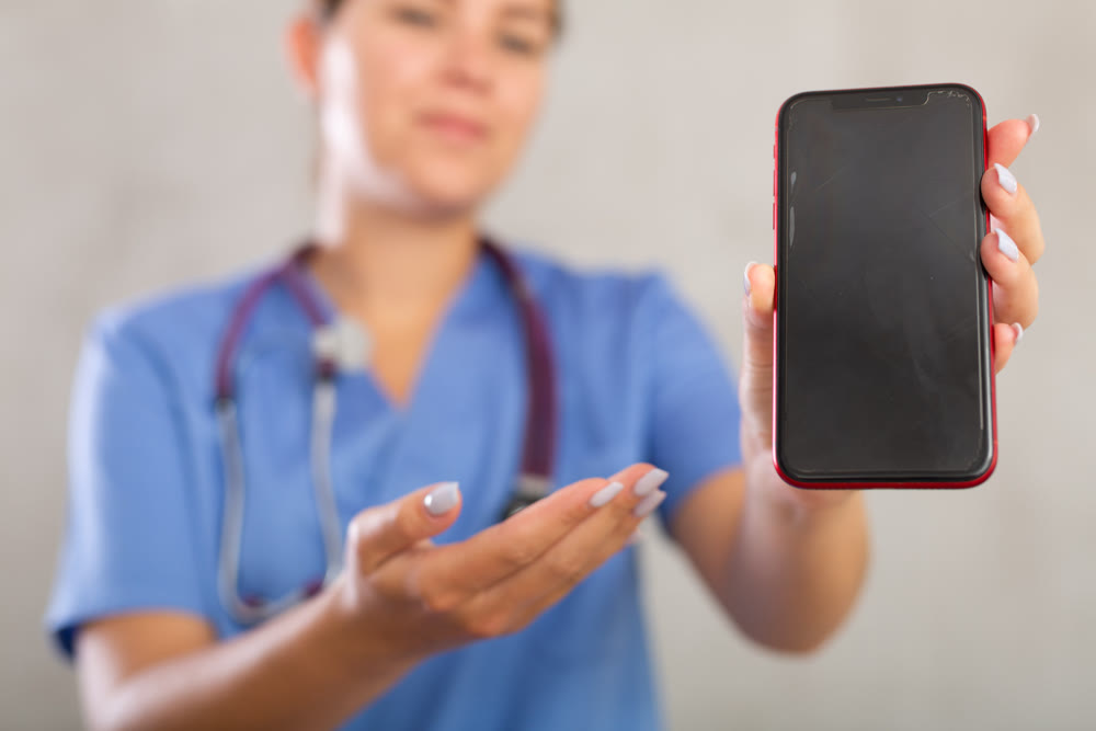 Young woman posing in medical uniform with phone