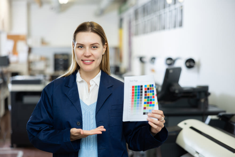 Woman employee of printing shop holds color chart in her hands
