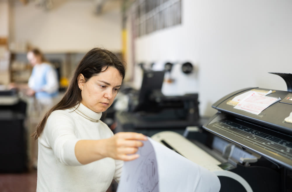 Female employee of the printing house checks the quality of the print