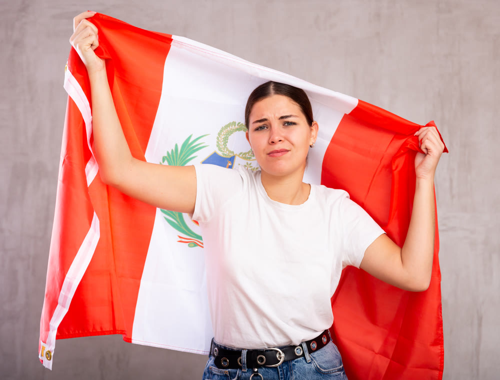 Sad young woman holding Peru flag against unicoloured background