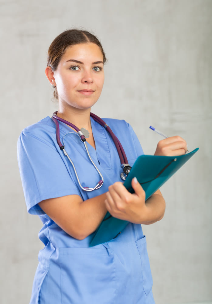 Young happy female nurse writing in file with papers