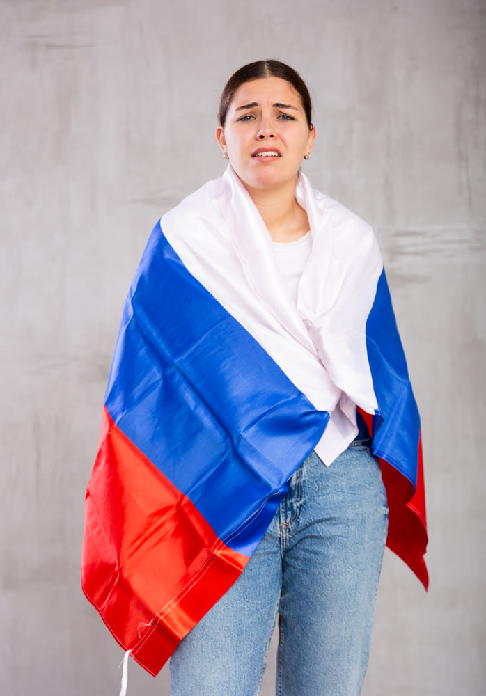 Sad young woman holding flag of Russia