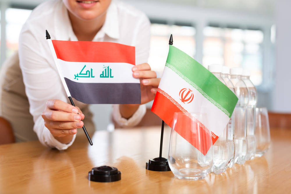 Woman secretary prepares an office for negotiations - she places flags of Iraq and Iran table