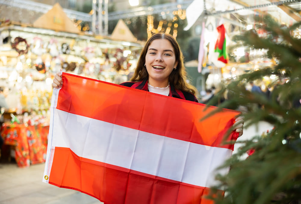 Happy girl with Austrian flag waving at New Year fair