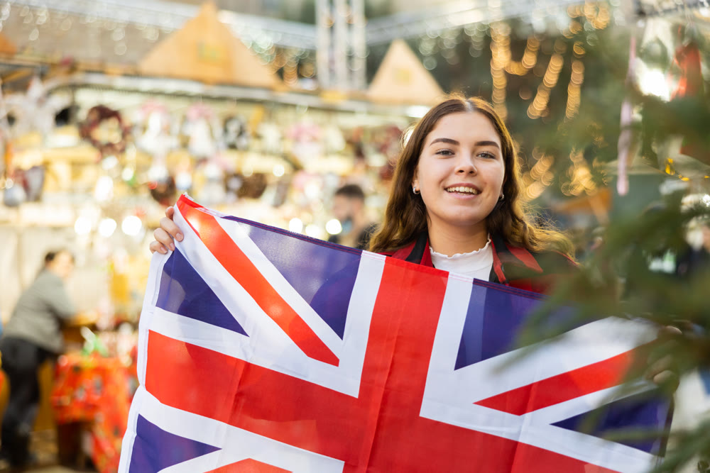 Cheerful girl with British flag at Christmas street fair