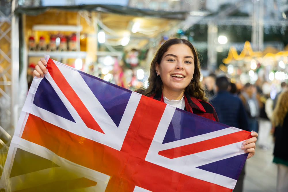 Happy girl with flag of United Kingdom at Christmas city market