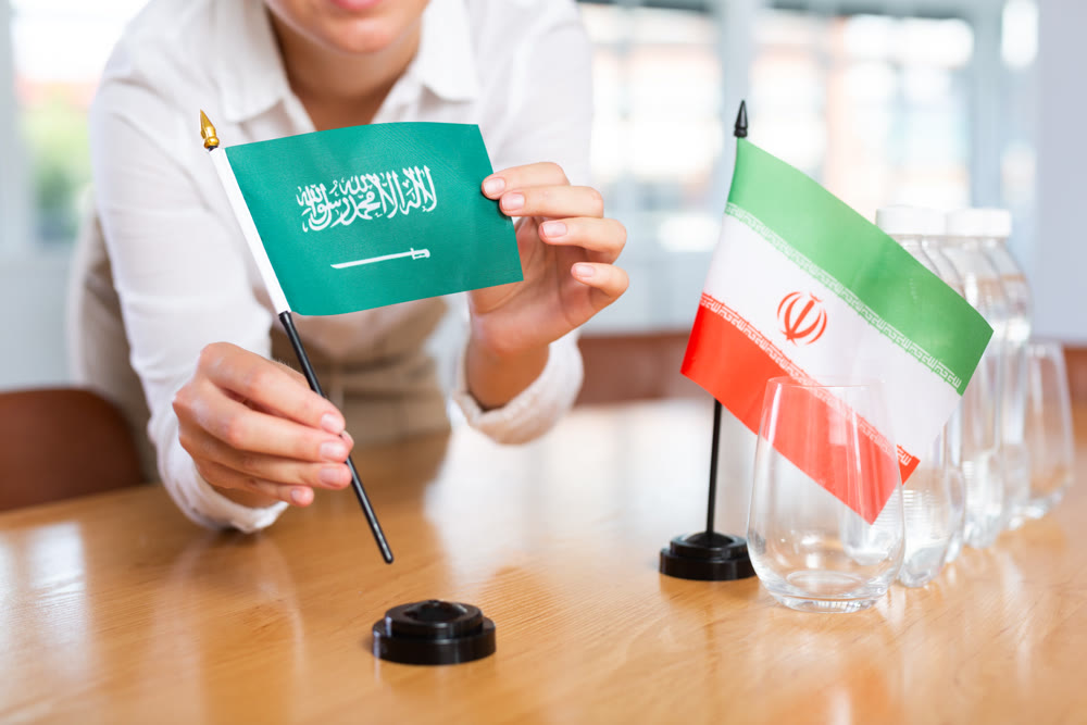 Preparing for business presentation - secretary places flags of Saudi Arabia and Iran on negotiating table