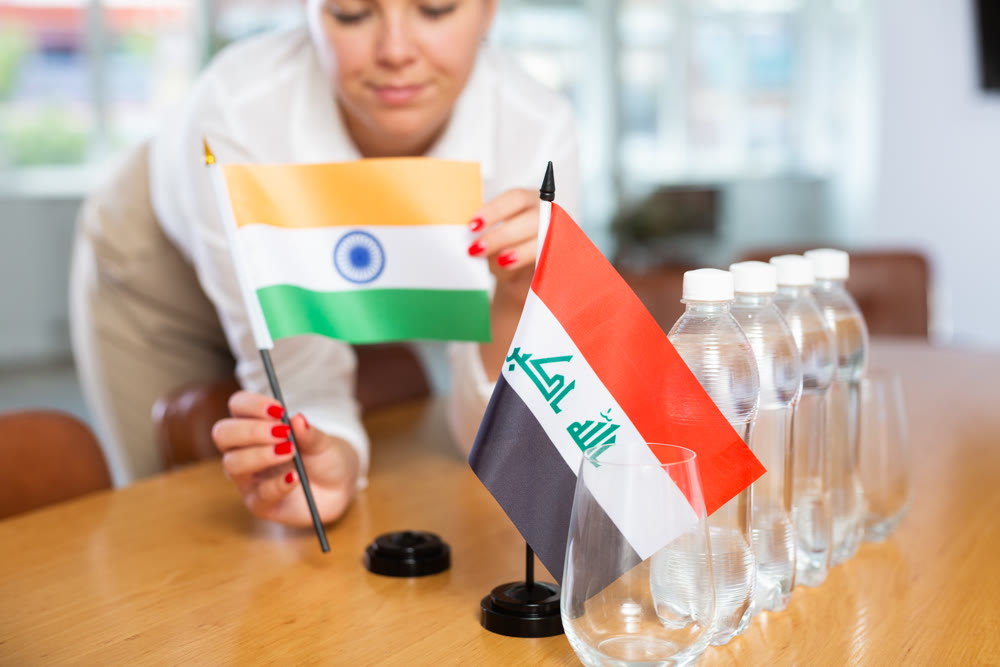 Unrecognizable girl sets midget flags of Iraq and India before international negotiations