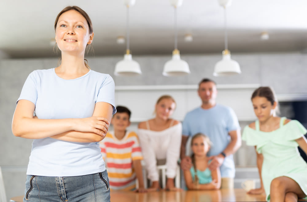 Smiling mum poses in cozy kitchen, large family with four children and husband are standing behind