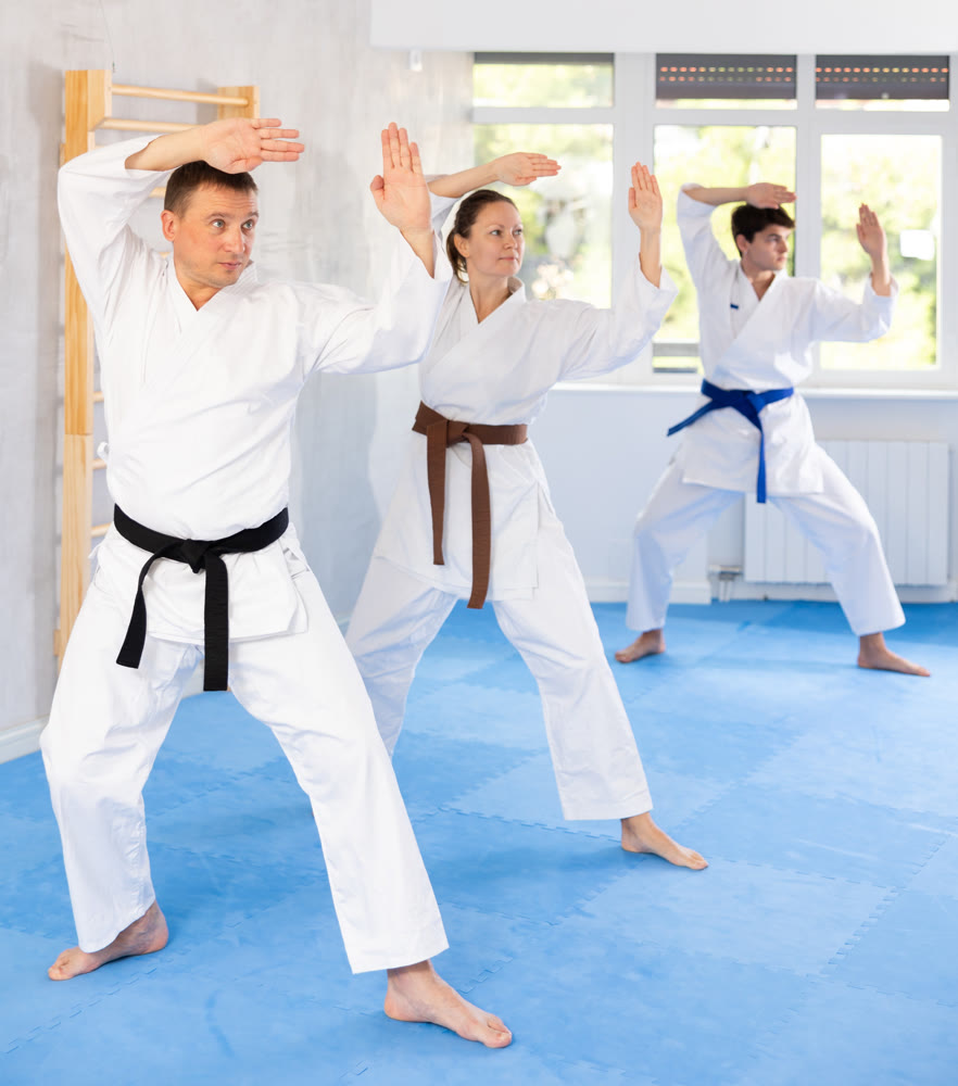 Group of people in kimonos try new fighting techniques at karate lessons