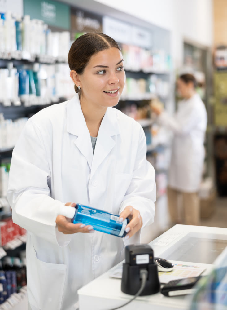 Female pharmacist scans qr code of product at checkout for sale in pharmacy