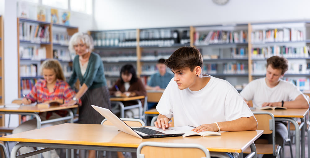 Teenager student sitting at desk in classroom at lesson in high school