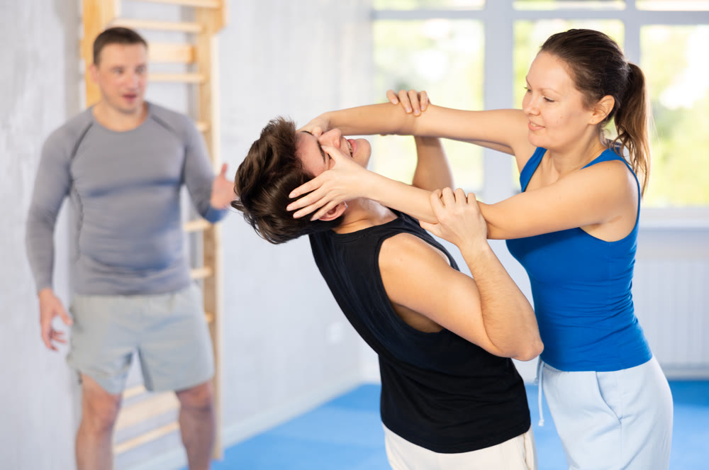 Guy paired up with woman to perform effective impact on pain points while learning self-defense.