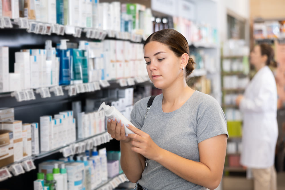 Young woman chooses and buys healing body lotion
