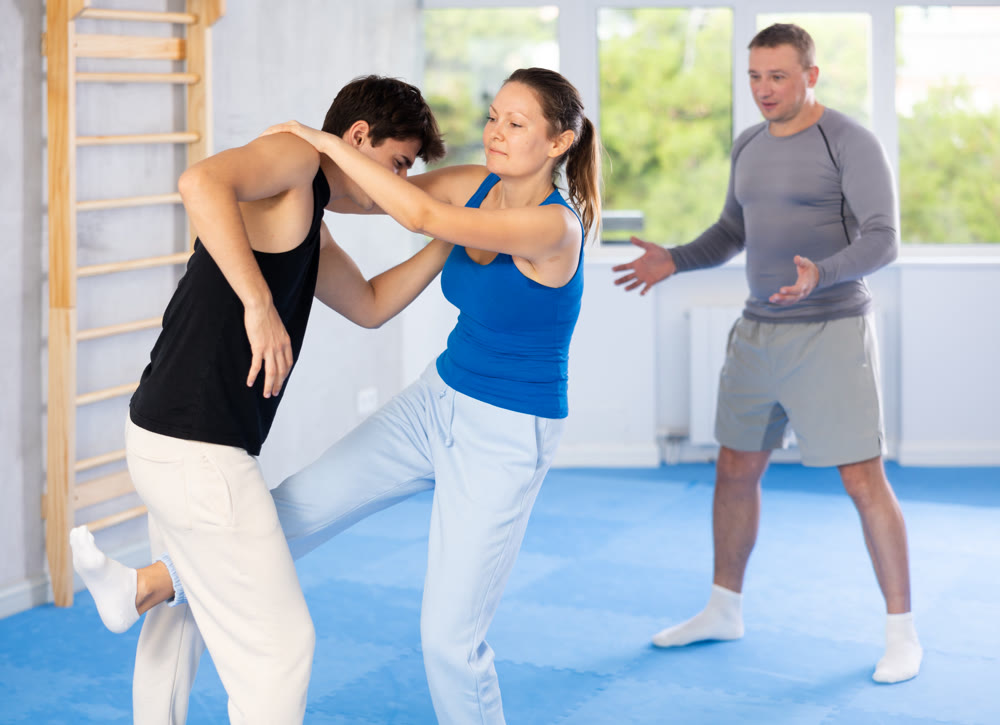 Guy paired up with woman to perform effective impact on pain points while learning self-defense.