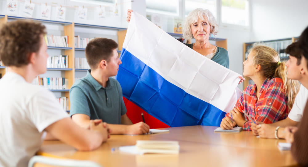 Interesting story about Russia while teaching high school students in school library. Teacher holds flag of Russia in her hands