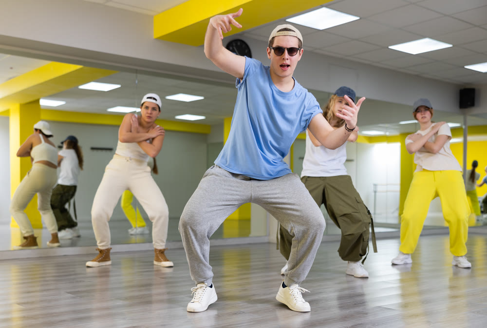 Emotional teen boy dancing with group of friends in dance studio. Hip hop generation