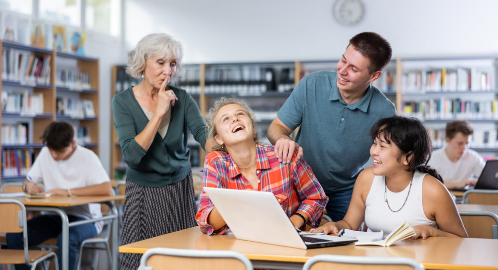 Elderly teacher asks to be quieter than noisy teenagers in school library