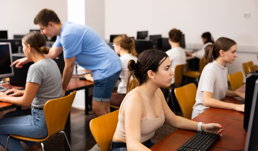 Smart Latin female teenager learning computer science while she is using a PC in the computer classroom