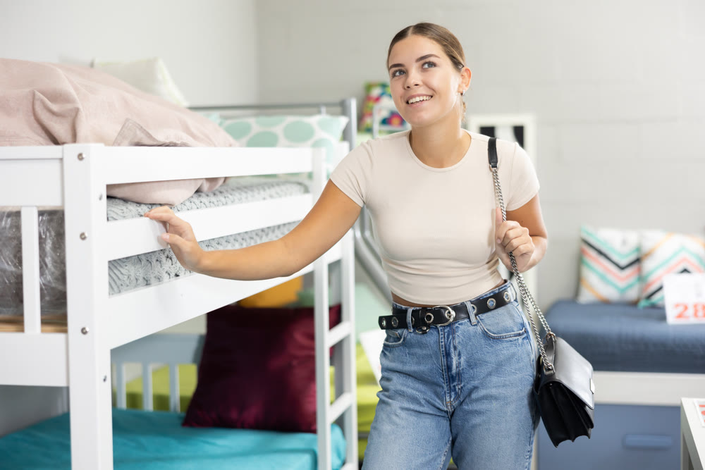 Young girl choosing new comfortable bunk bed in furniture store